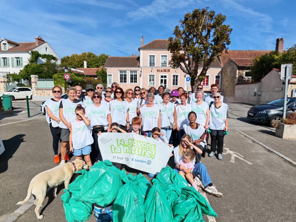 Photo de groupe des bénévoles et des sacs de déchets ramassés devant la mairie